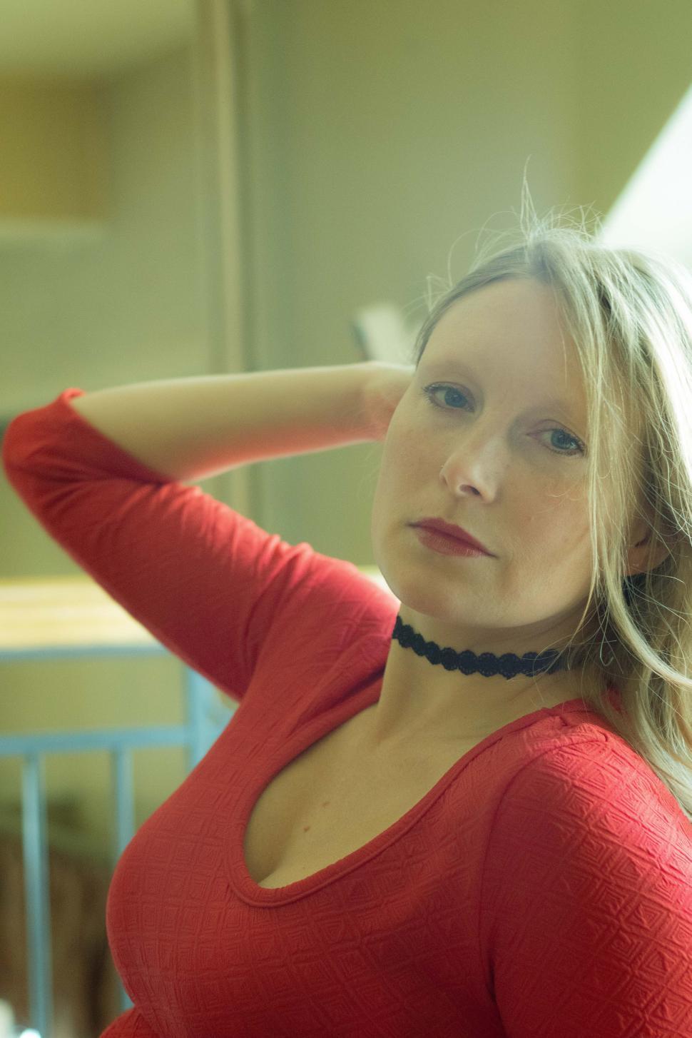 Free Image of Woman in red dress poses gracefully indoors with soft lighting 