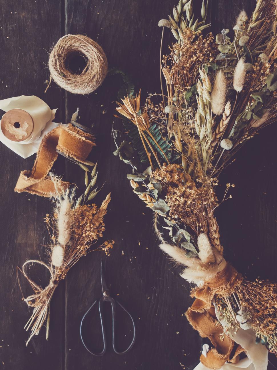 Free Image of Crafting dried flower arrangements on rustic wooden table 