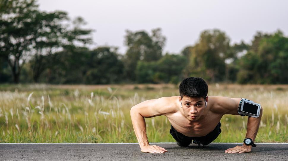 Free Image of Shirtless man does push up in the street 