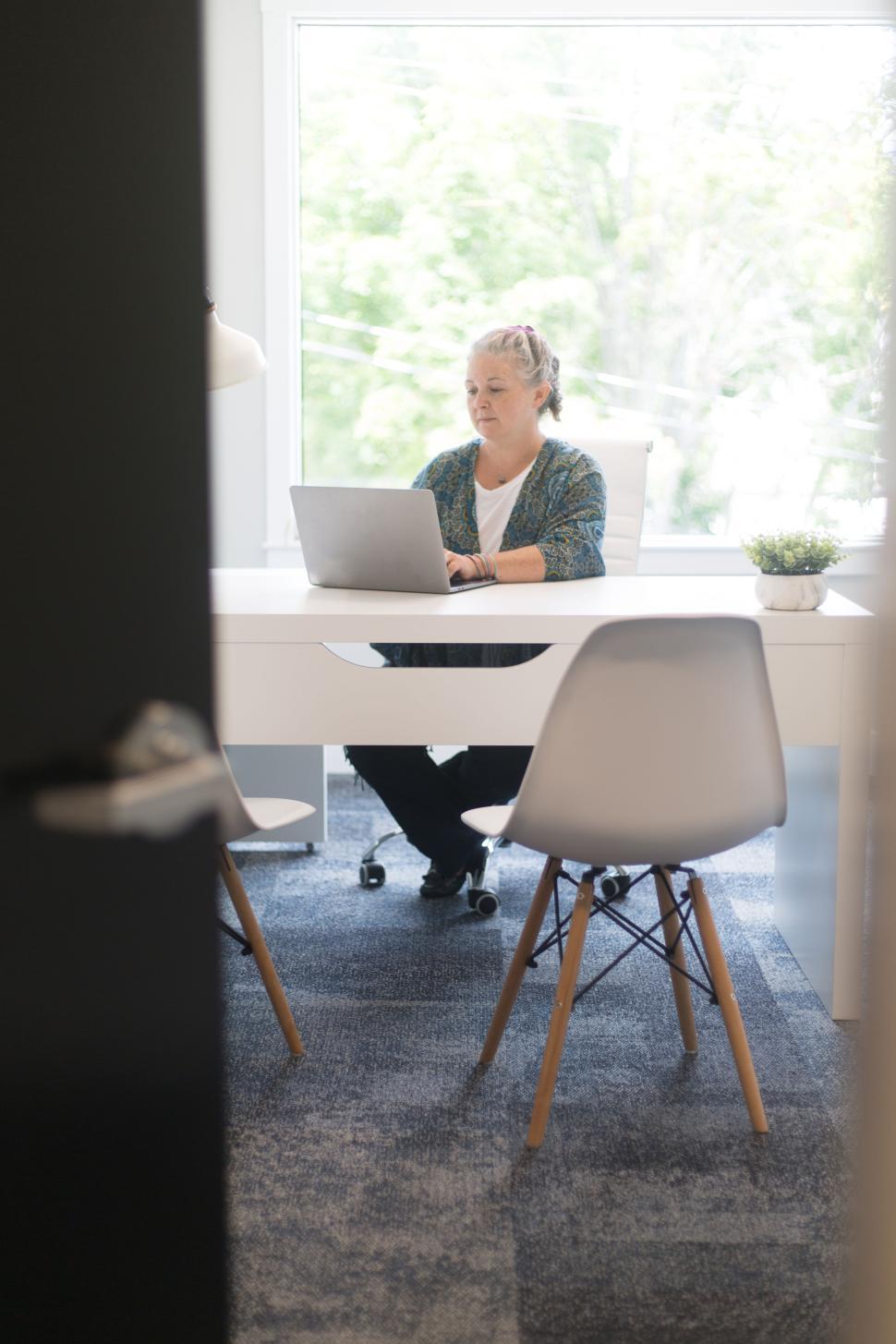 Free Image of Senior woman working on laptop in modern office setting 