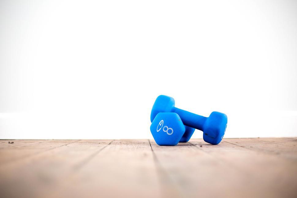Free Image of Weights lying on a wooden floor in a bright space 