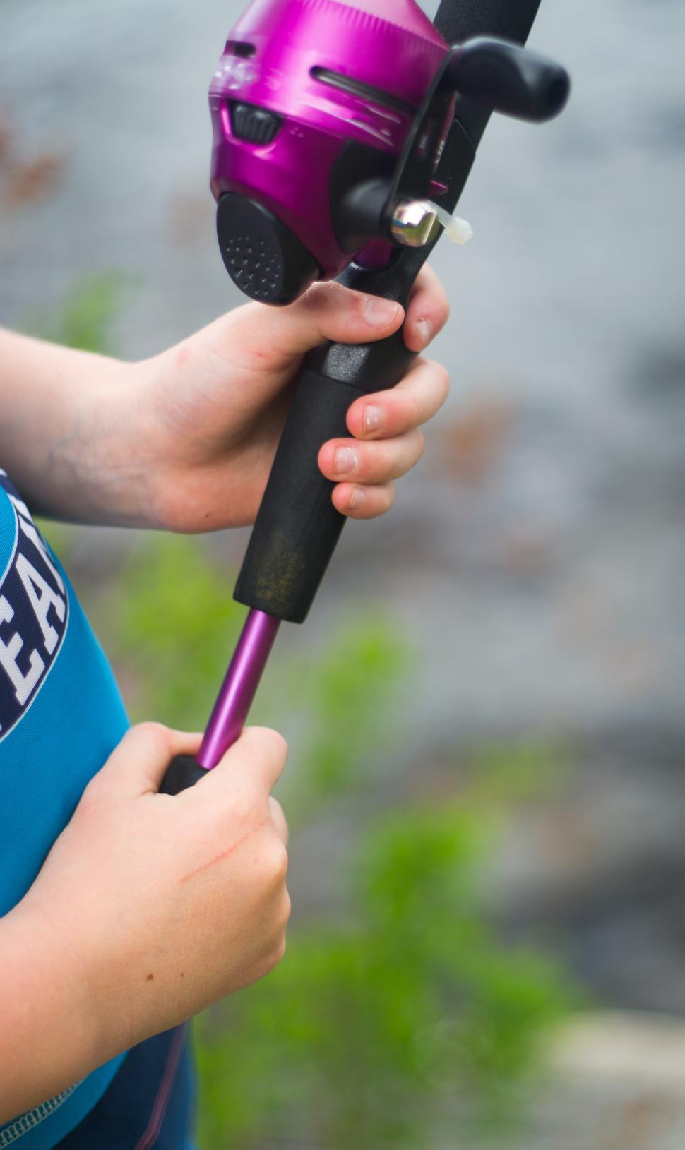 Free Image of Young angler enjoys fishing with purple rod by the water s edge in summer 