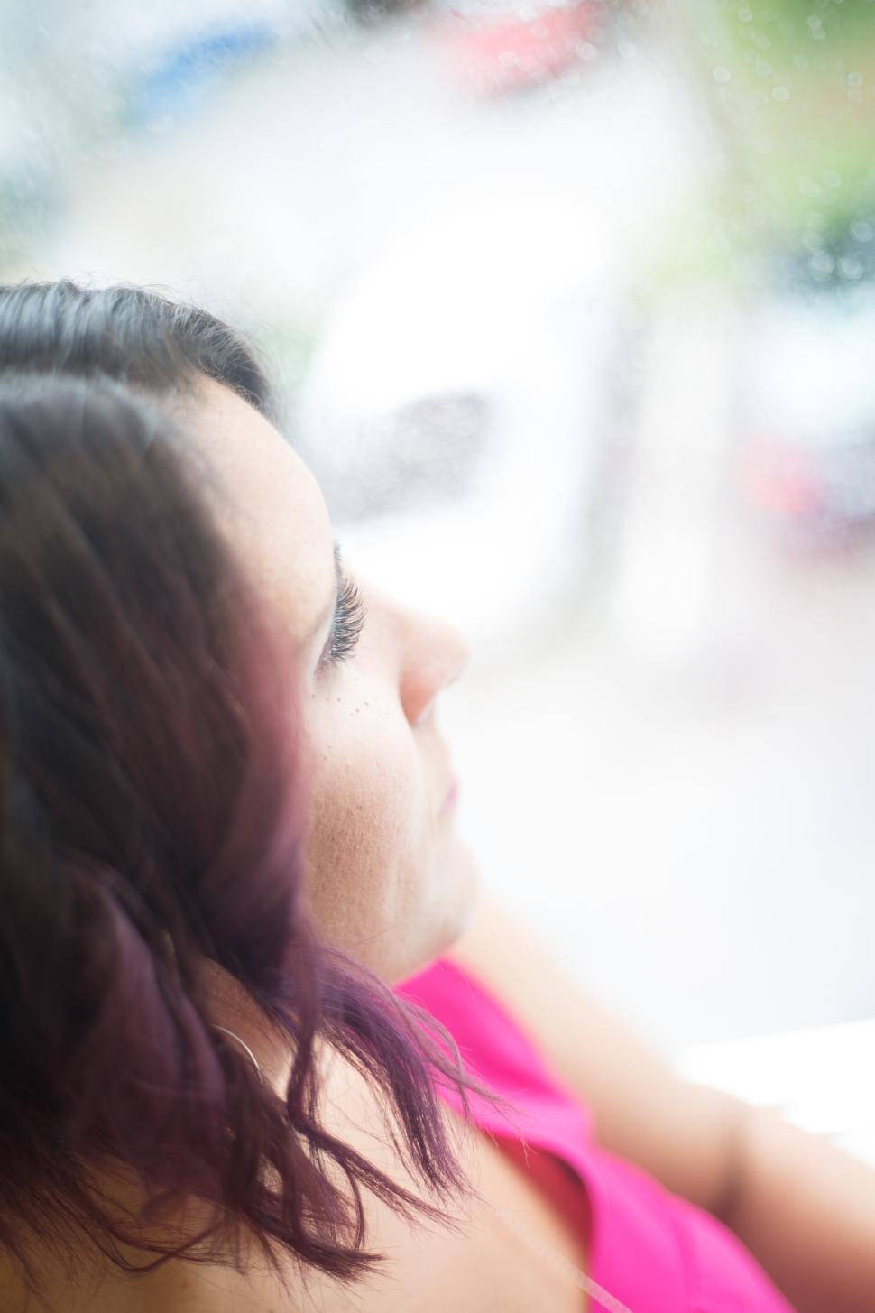Free Image of Woman gazing out a window on a rainy day 