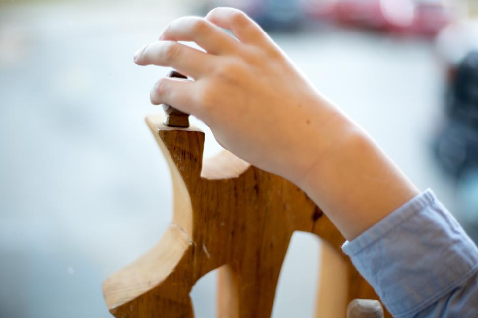 Free Image of Hand adjusting wooden sculpture near window in a creative space 