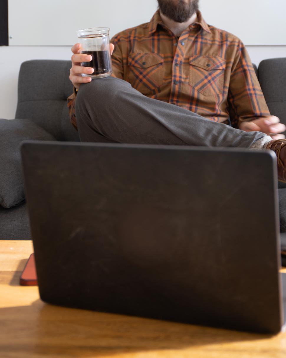 Free Image of Man enjoying coffee while working on laptop at home 
