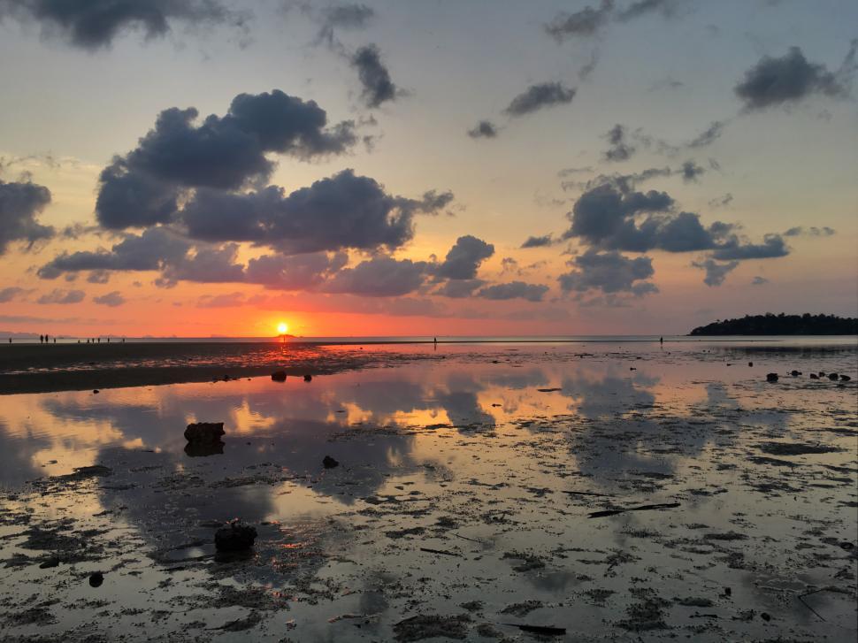 Free Image of Sunset over calm waters at a serene beach location 