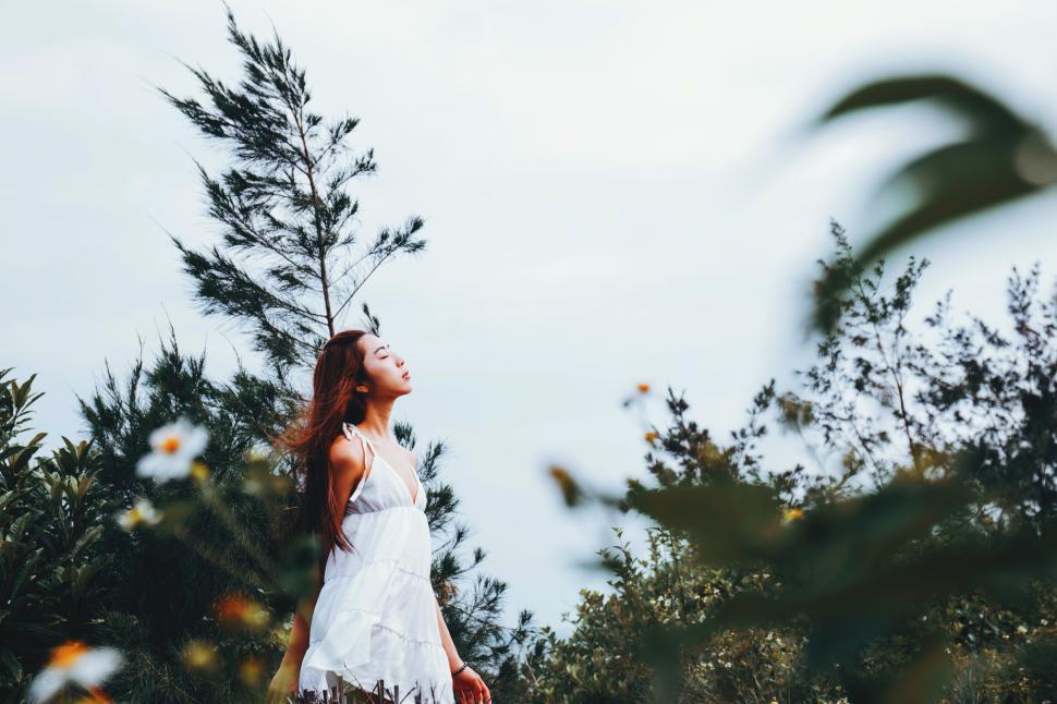 Free Image of Young woman enjoying nature by tall trees and flowers 