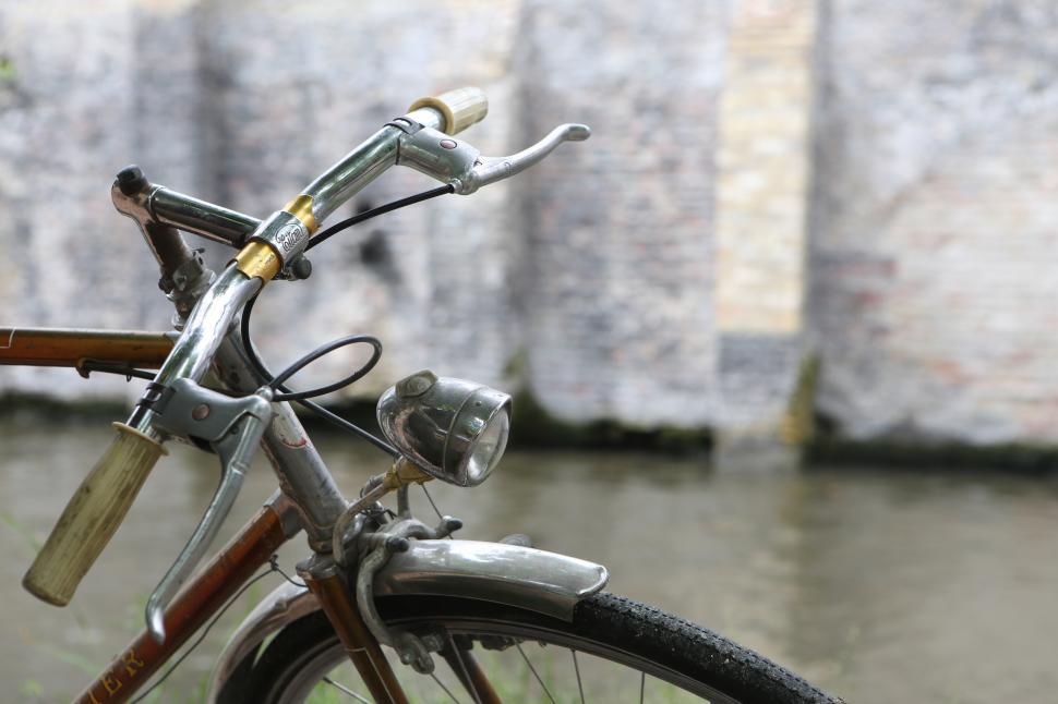 Free Image of Classic bicycle parked by the calm riverbank 