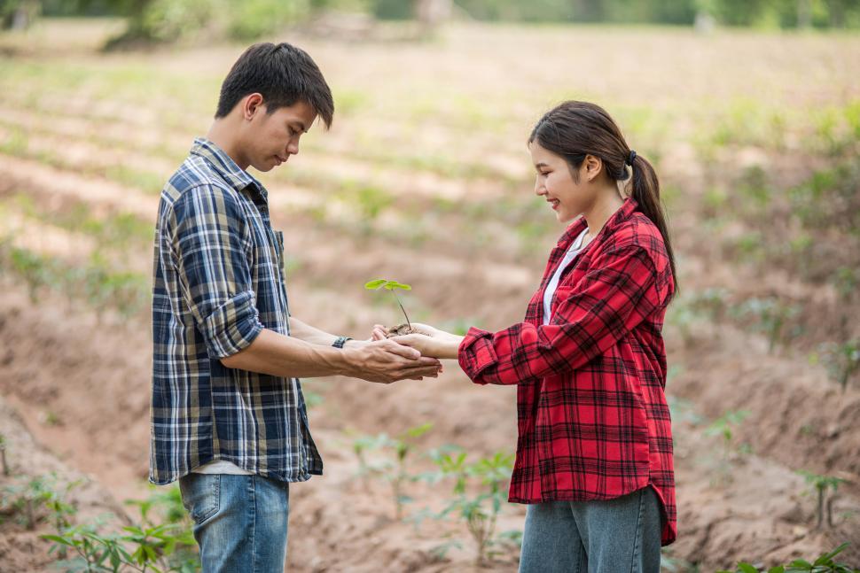 Free Image of Men and women standing and holding saplings. 