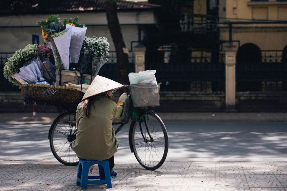 Free Image of Flower vendor resting by the roadside on a sunny day in the city 