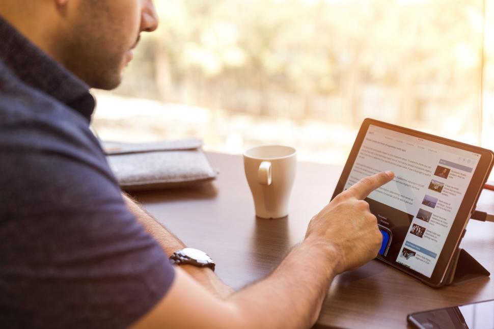 Free Image of Person using tablet while seated at a wooden table 