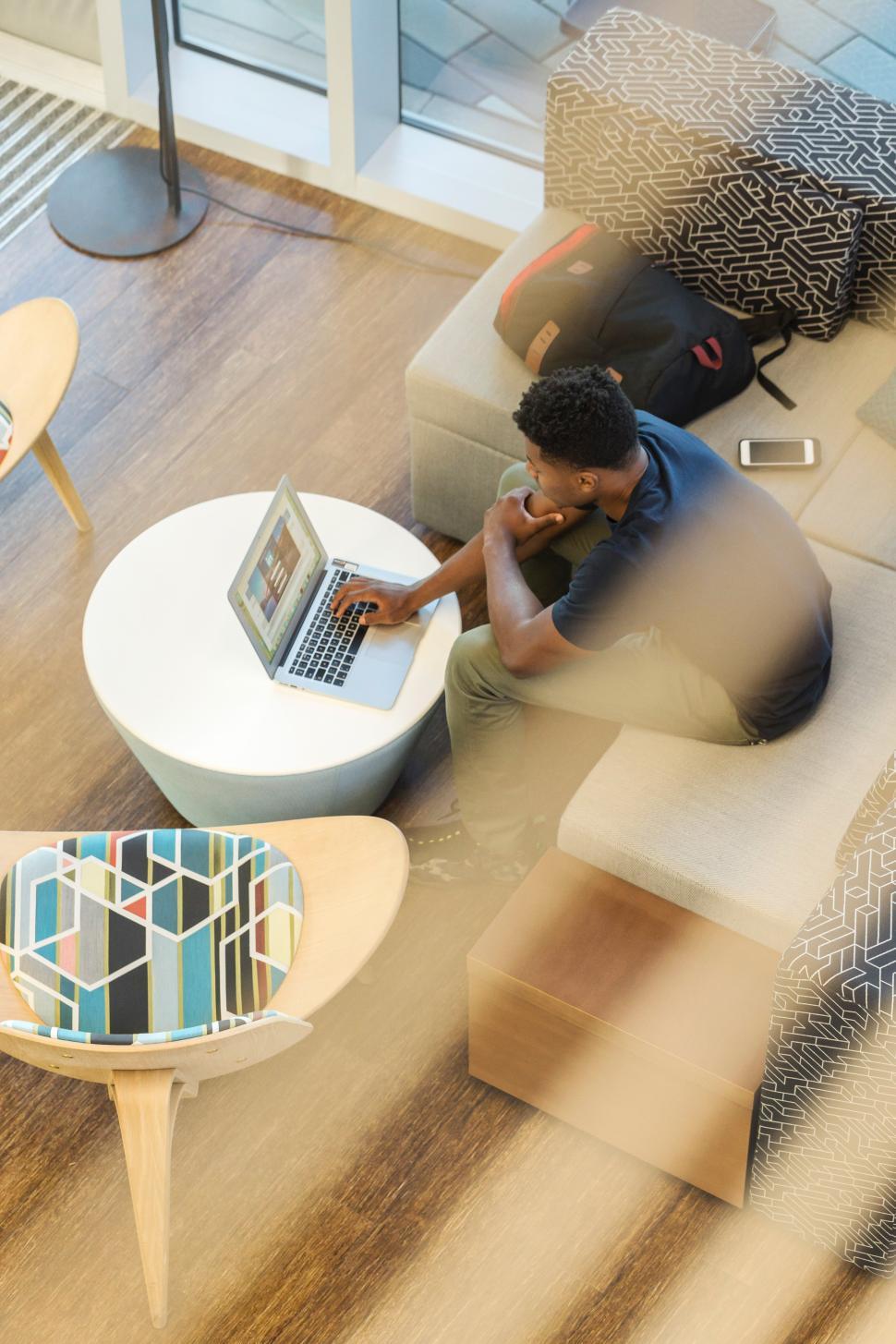 Free Image of Young man working on laptop in modern cafe setting 