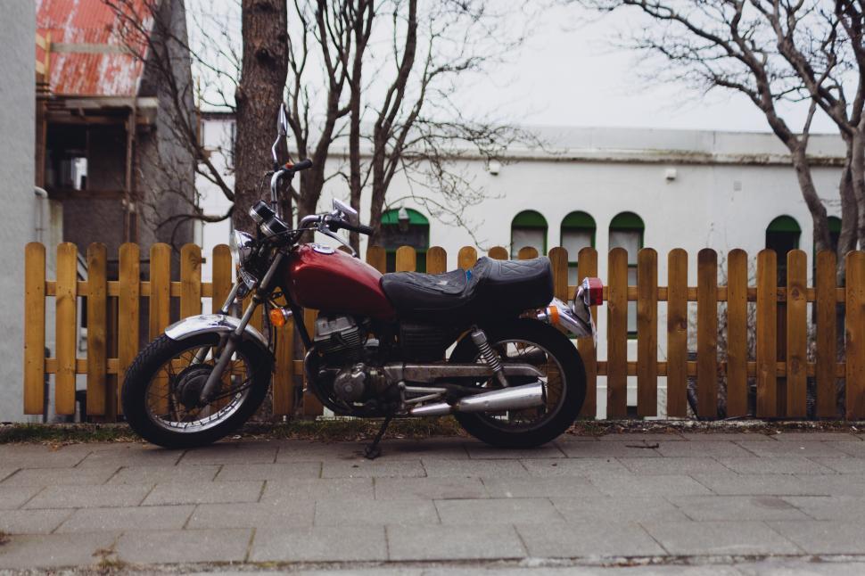 Free Image of Vintage motorcycle parked by wooden fence in urban setting 