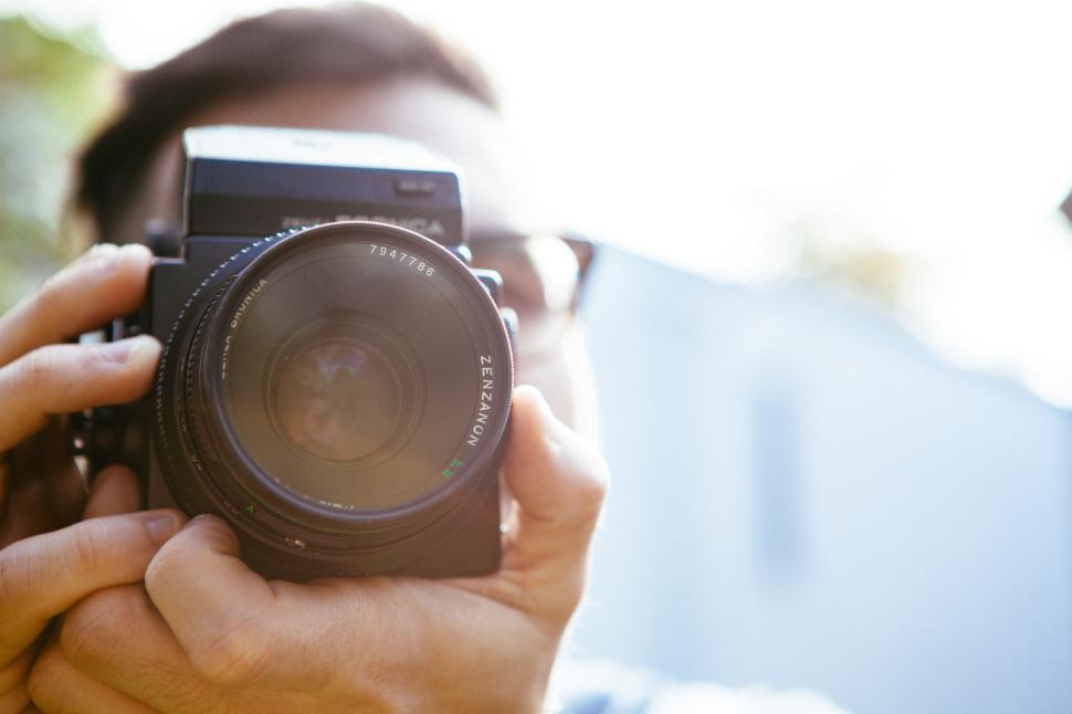 Free Image of Man holding camera in outdoor setting during daylight 
