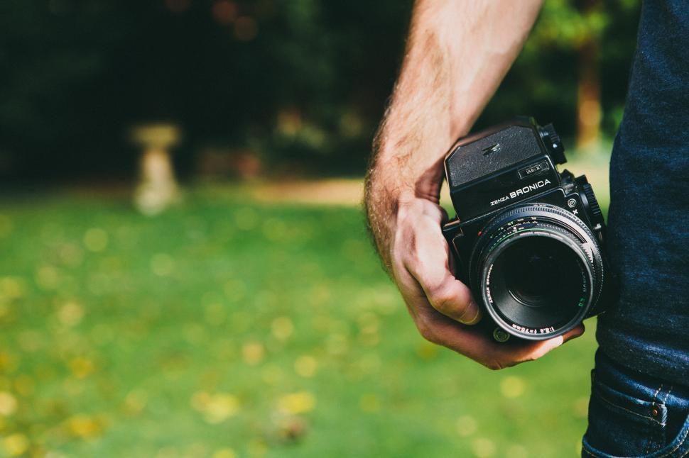 Free Image of Passionate photographer holds camera in lush park setting 