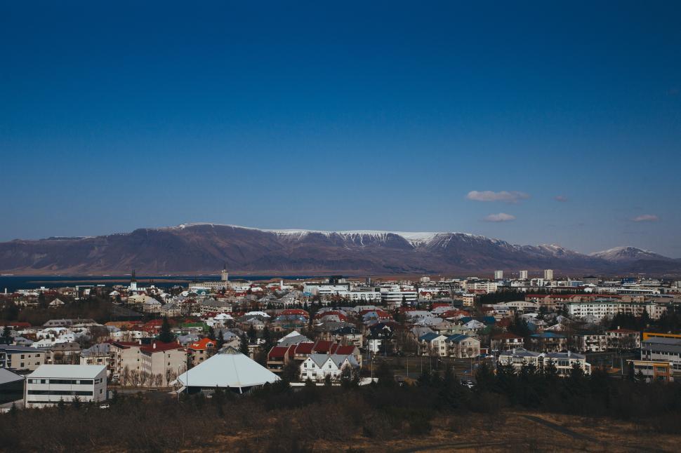 Free Image of Snow-capped mountains tower over Reykjavik cityscape 