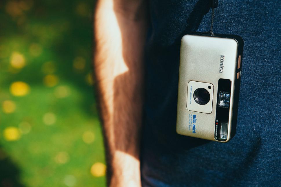 Free Image of Nostalgic camera hangs by a person s side outdoors 