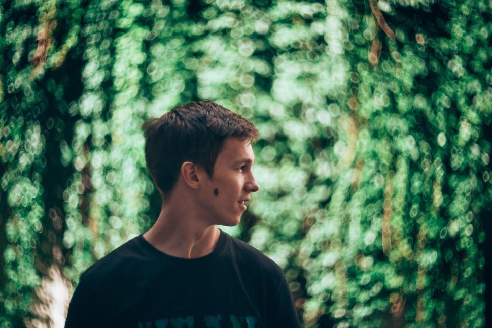 Free Image of Young man standing amidst green foliage during daytime 