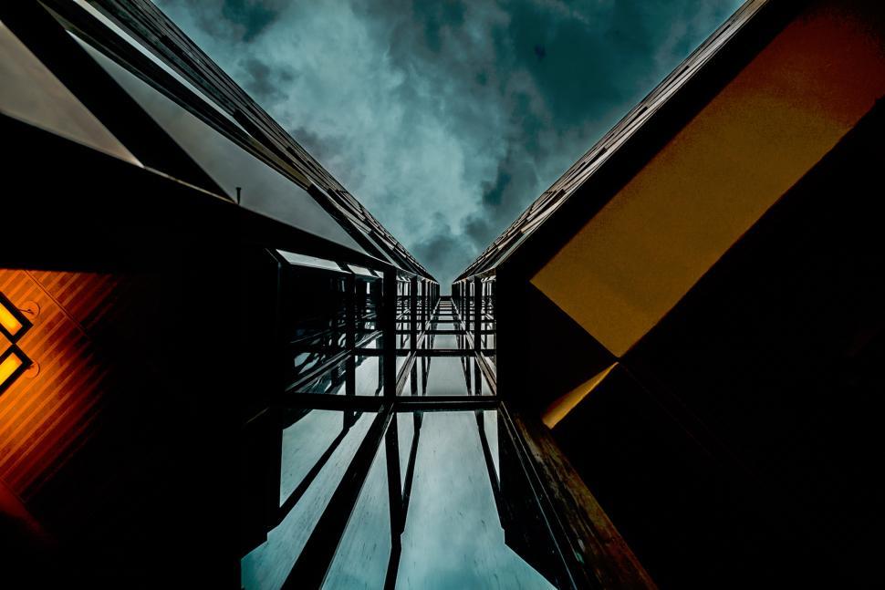 Free Image of Looking up at tall modern buildings under dramatic cloudy sky 