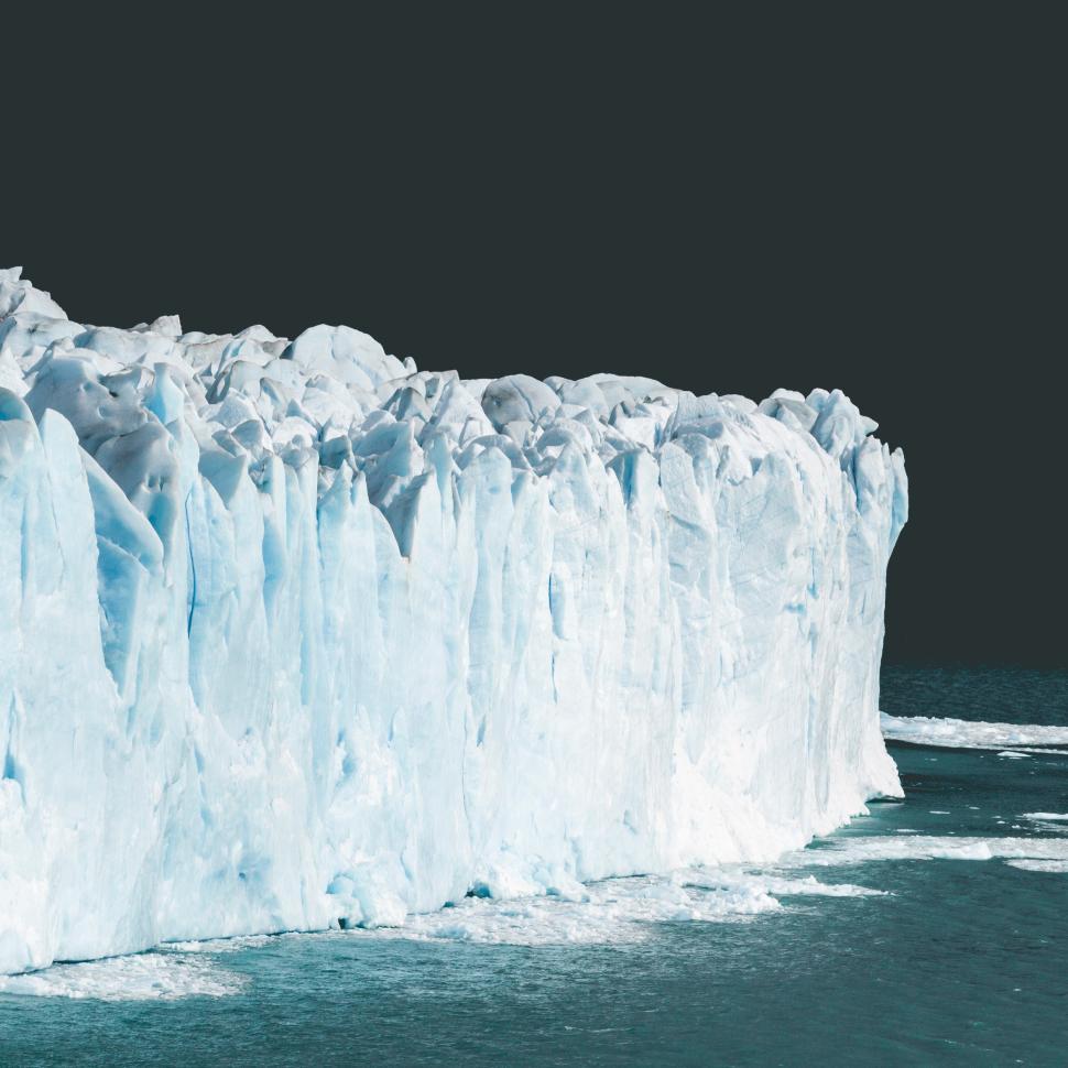 Free Image of Glacier towers over tranquil ocean waters under a twilight sky 