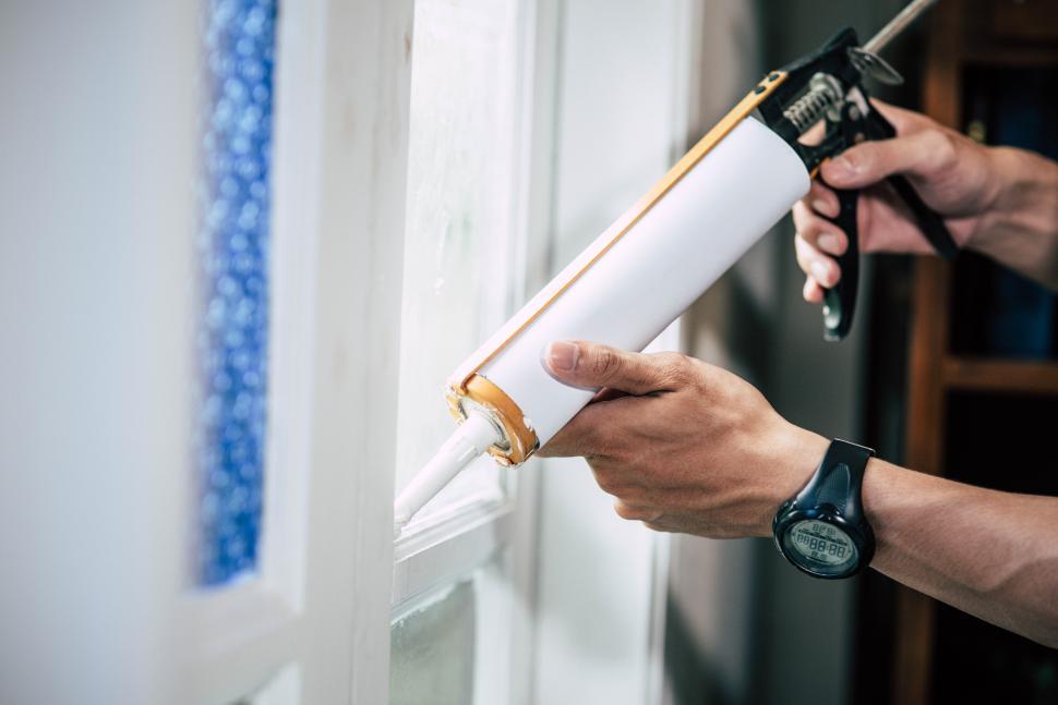 Free Image of The carpenter holds the glue and attaches to the window. 