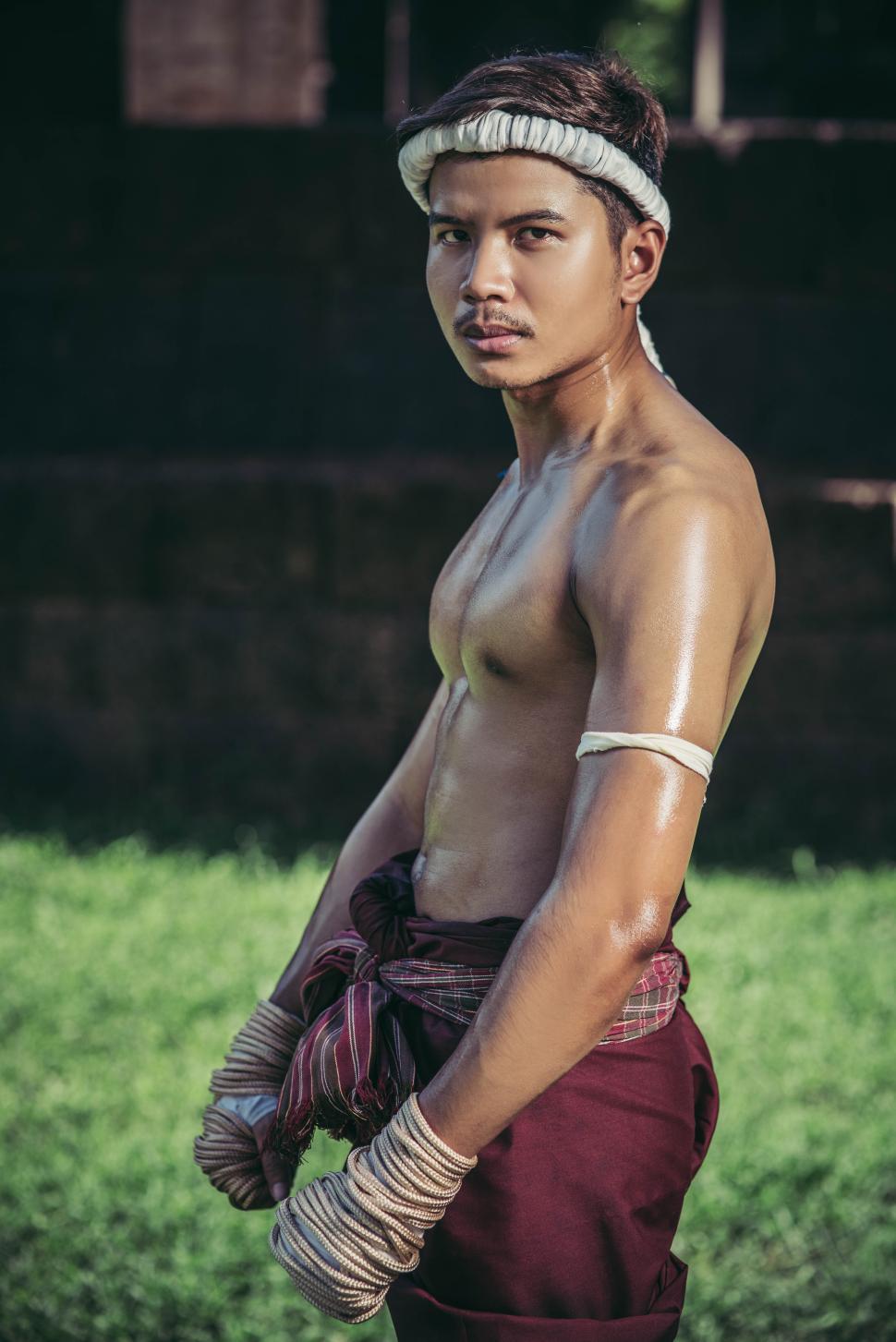 Free Image of Thai boxers wrap the tape in the hands and stand on the lawn. 