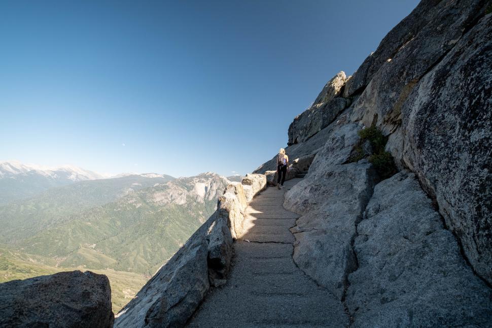 Free Image of Hiking along rocky trail in mountainous region during clear blue skies 