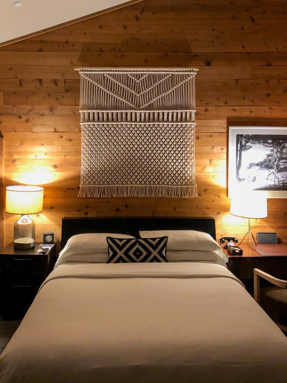 Free Image of Cozy bedroom with wooden walls and decorative wall hanging at nighttime 