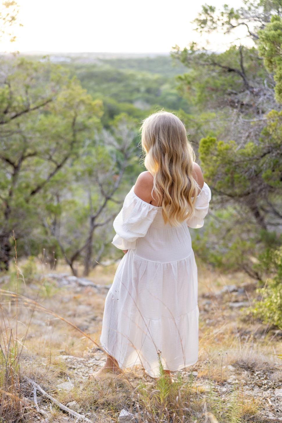 Free Image of Woman in white dress enjoys peaceful nature view during golden hour 