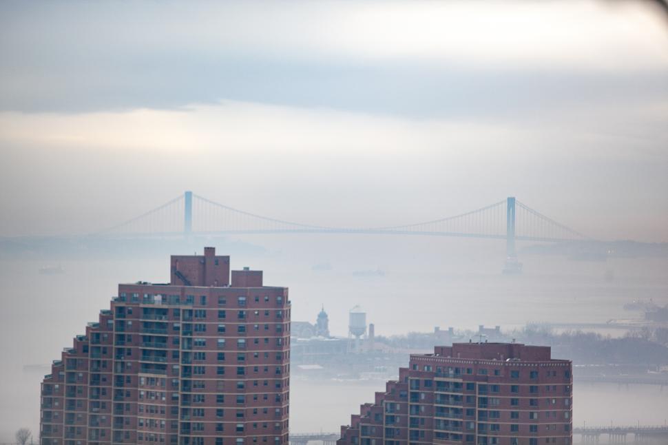 Free Image of Foggy skyline view of a bridge and city buildings during dawn 