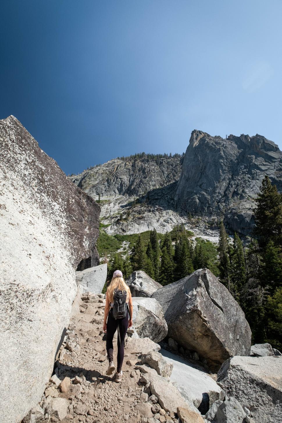 Free Image of Hiker ascending rocky trail in mountainous landscape on sunny day 