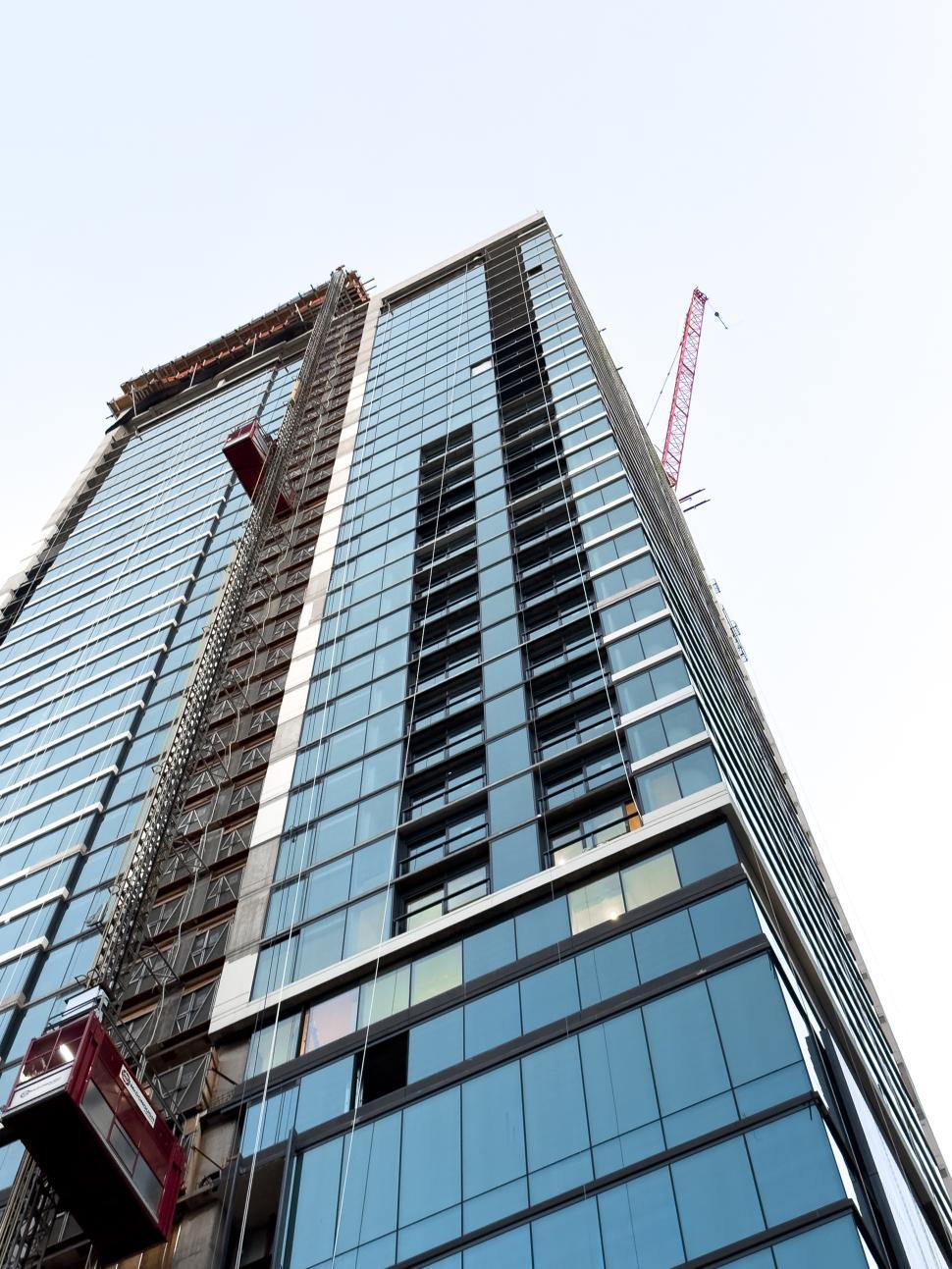 Free Image of Construction of a modern skyscraper with cranes and reflective glass panels 