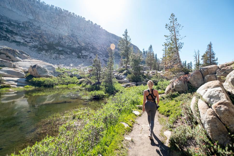 Free Image of Woman hiking along a scenic trail by a serene lake in nature 