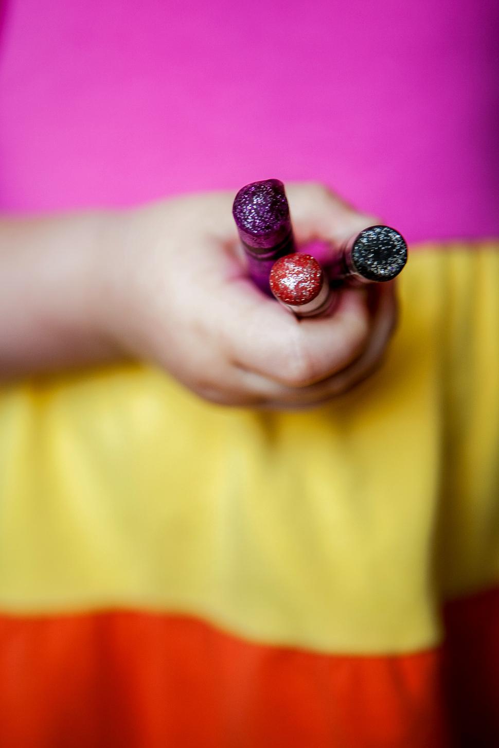 Free Image of Child holds colorful glitter markers during creative activity 