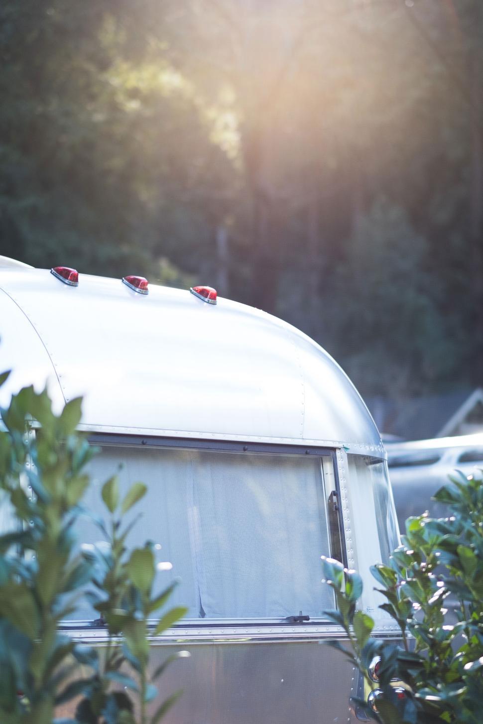 Free Image of Vintage trailer glows in sunlight amid lush greenery 