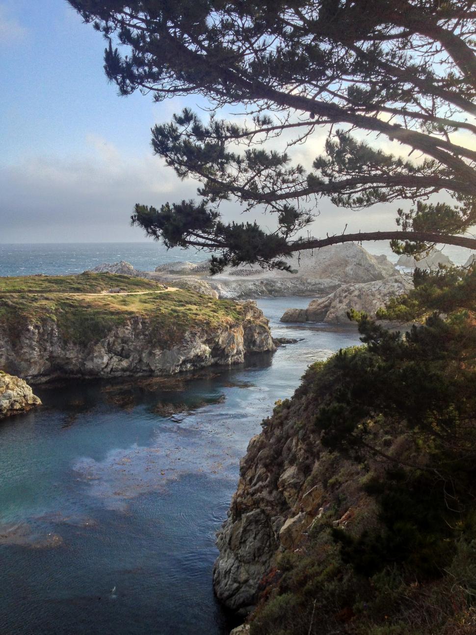 Free Image of Coastal view of rocky cliffs and calm waters under a cloudy sky 