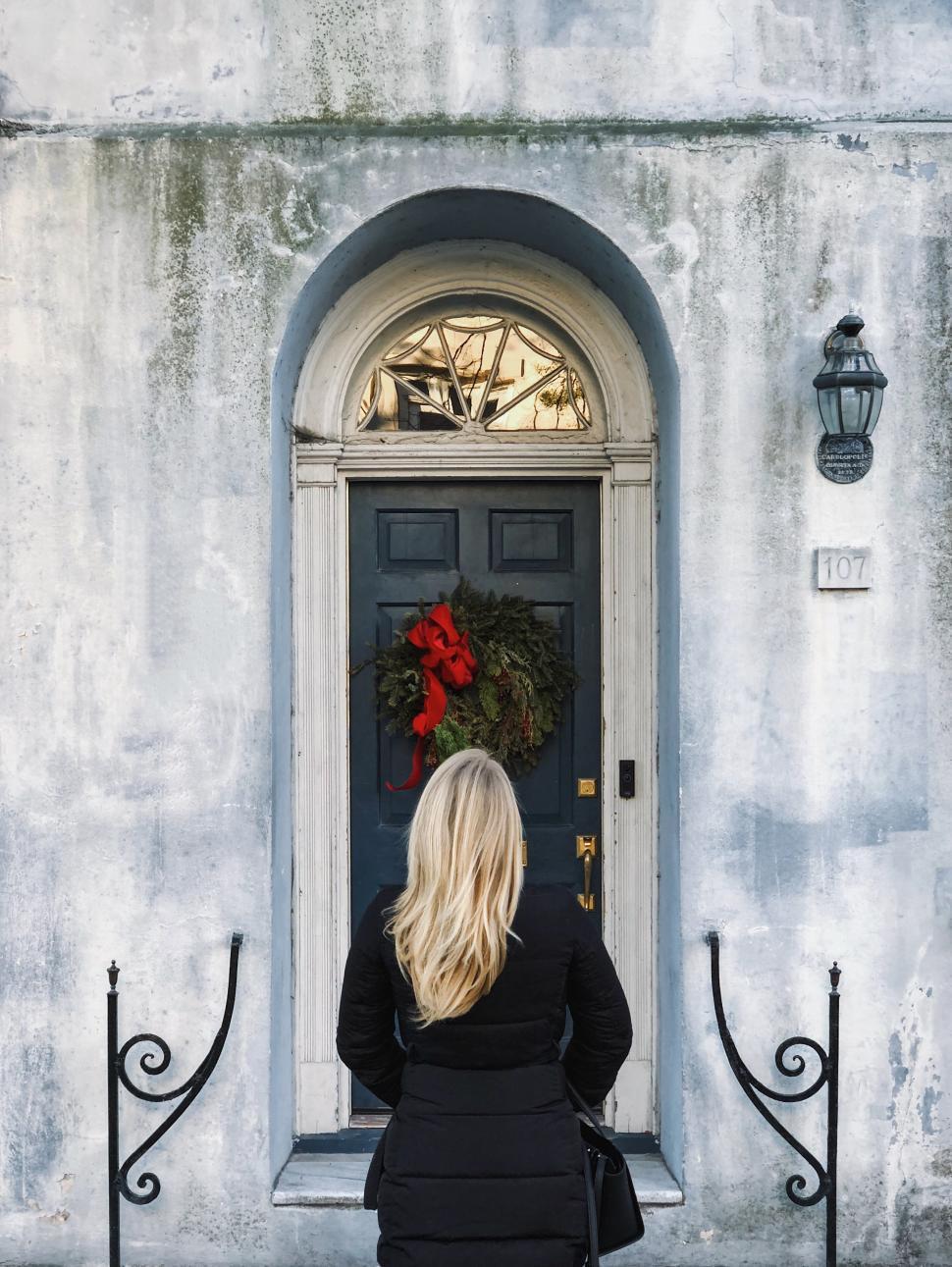 Free Image of Woman admiring a decorated door during the festive season 