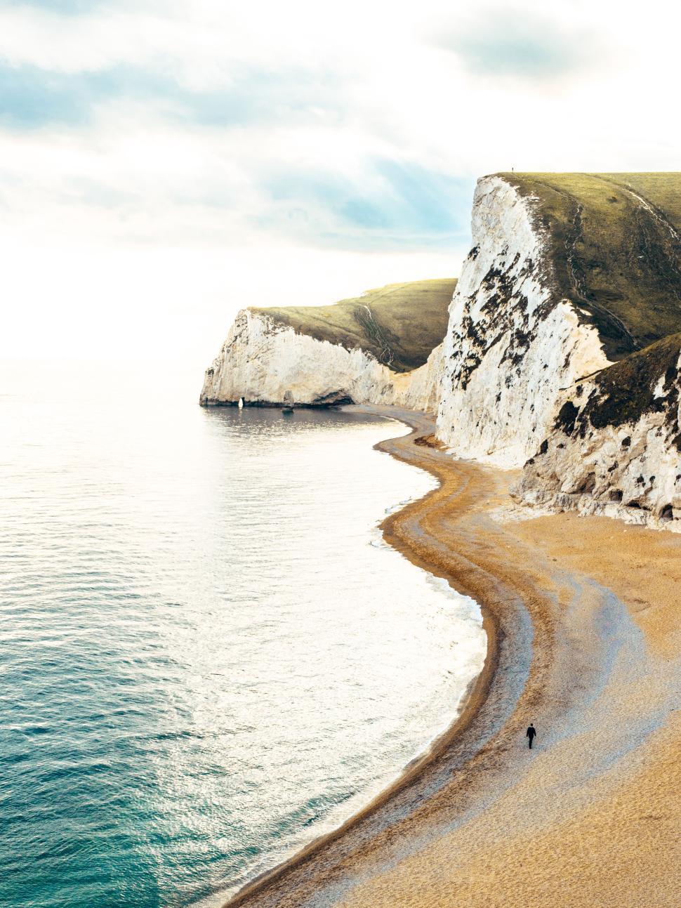 Free Image of Coastline walk along sandy beach near white cliffs at sunset 