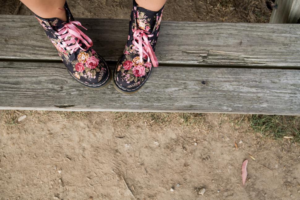 Free Image of Colorful floral boots resting on a wooden bench outdoors 