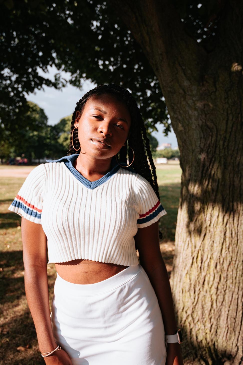 Free Image of Young woman posing under a tree during late afternoon sunshine 