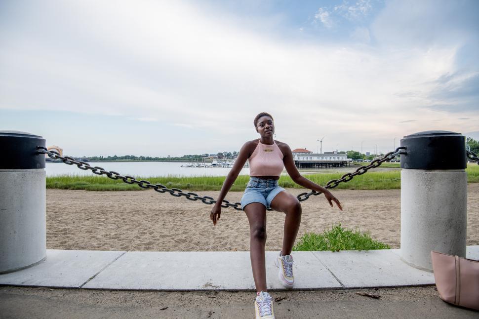 Free Image of Young woman relaxing by the waterfront in a casual outfit 