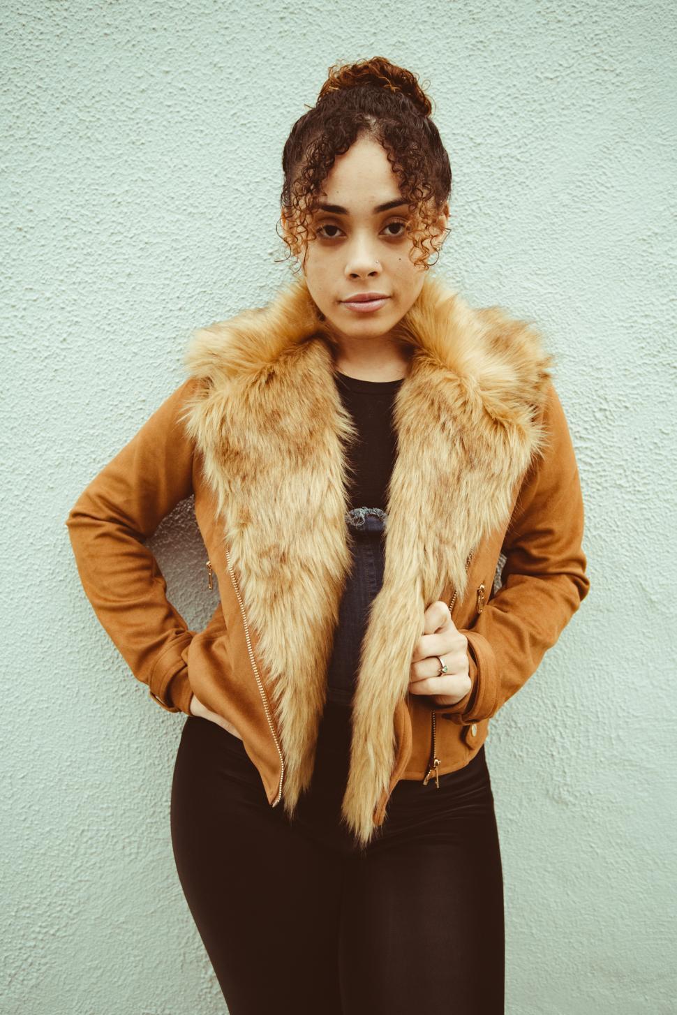 Free Image of Model poses confidently in stylish brown jacket against textured wall 