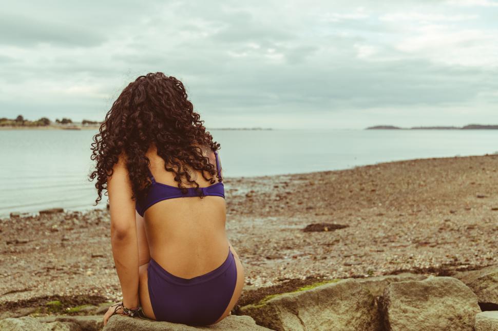 Free Image of Woman in swimwear enjoying a tranquil moment by the water s edge 