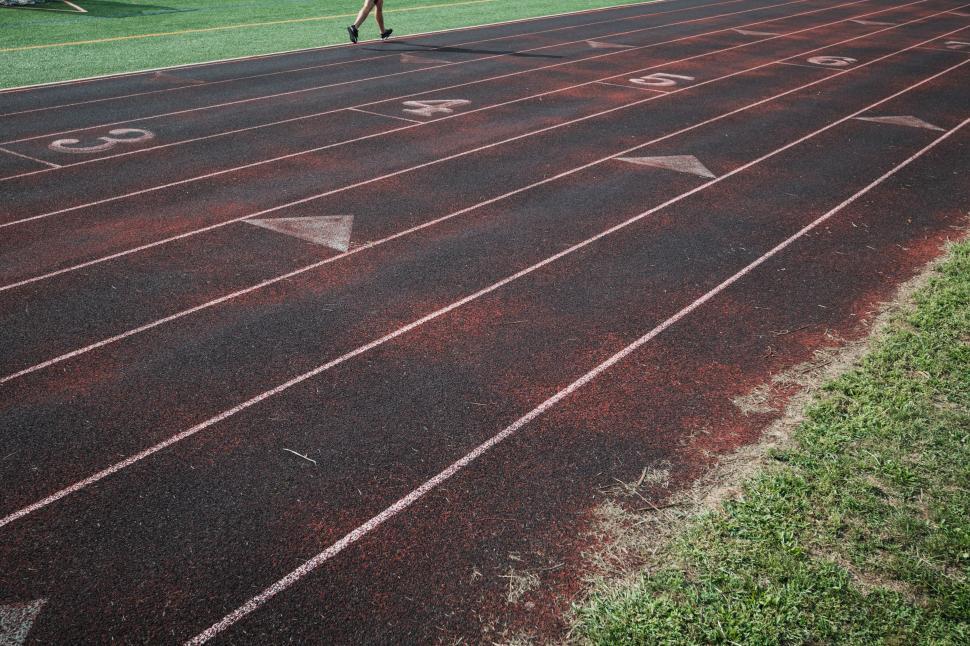 Free Image of Runner practices on a track field during late afternoon hours 