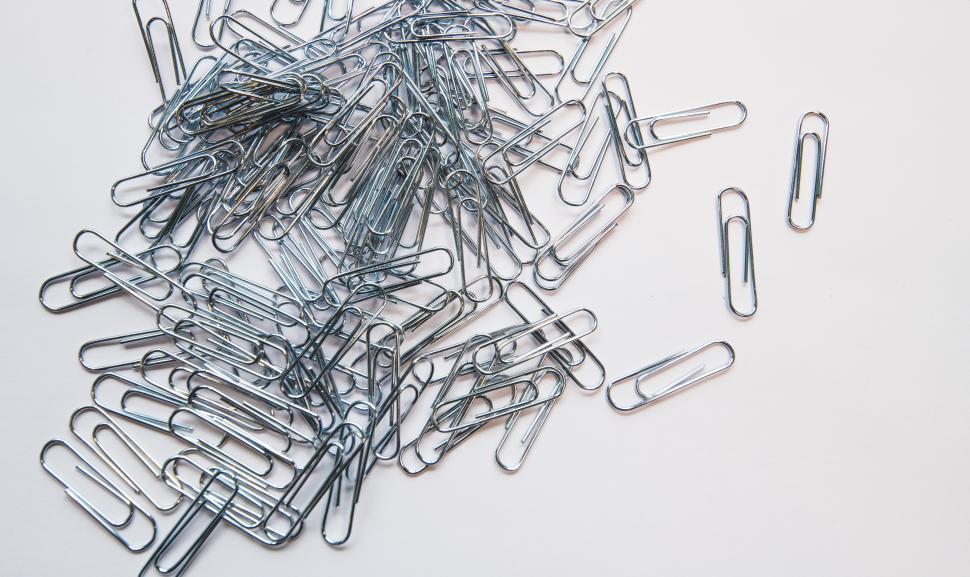 Free Image of Silver paper clips scattered on a white surface 