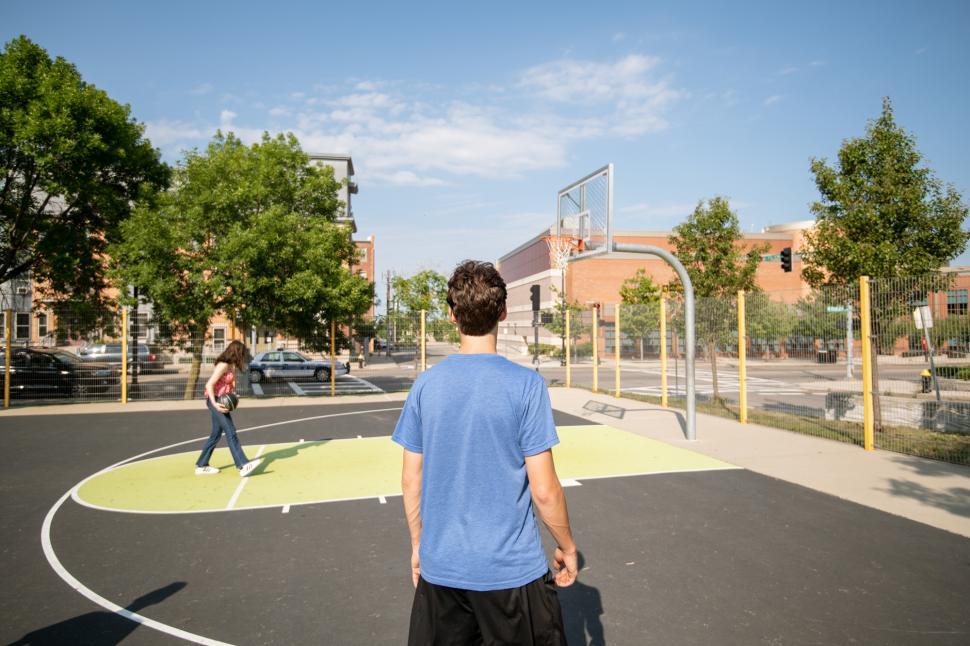 Free Image of Young adults enjoying basketball in a sunny urban playground 