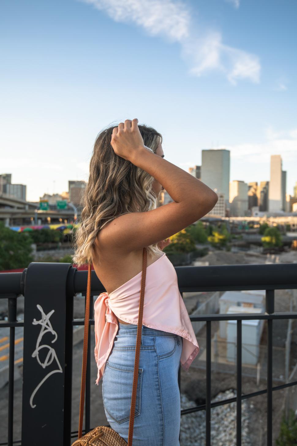 Free Image of Woman enjoying city view by the river at sunset 
