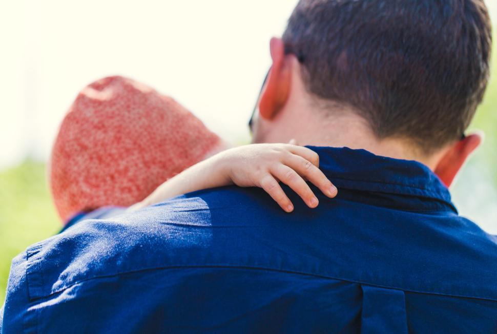 Free Image of Father carrying child in a sunny outdoor setting 