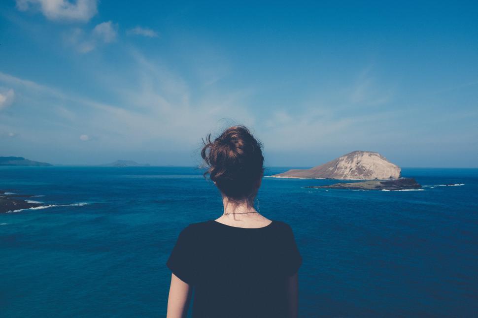 Free Image of Woman gazes at ocean view from a cliff overlooking an island 