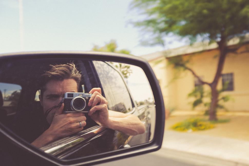 Free Image of Man captures moment while leaning out of car window 
